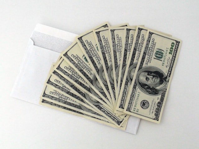 one hundred dollar bills on top of an envelope
